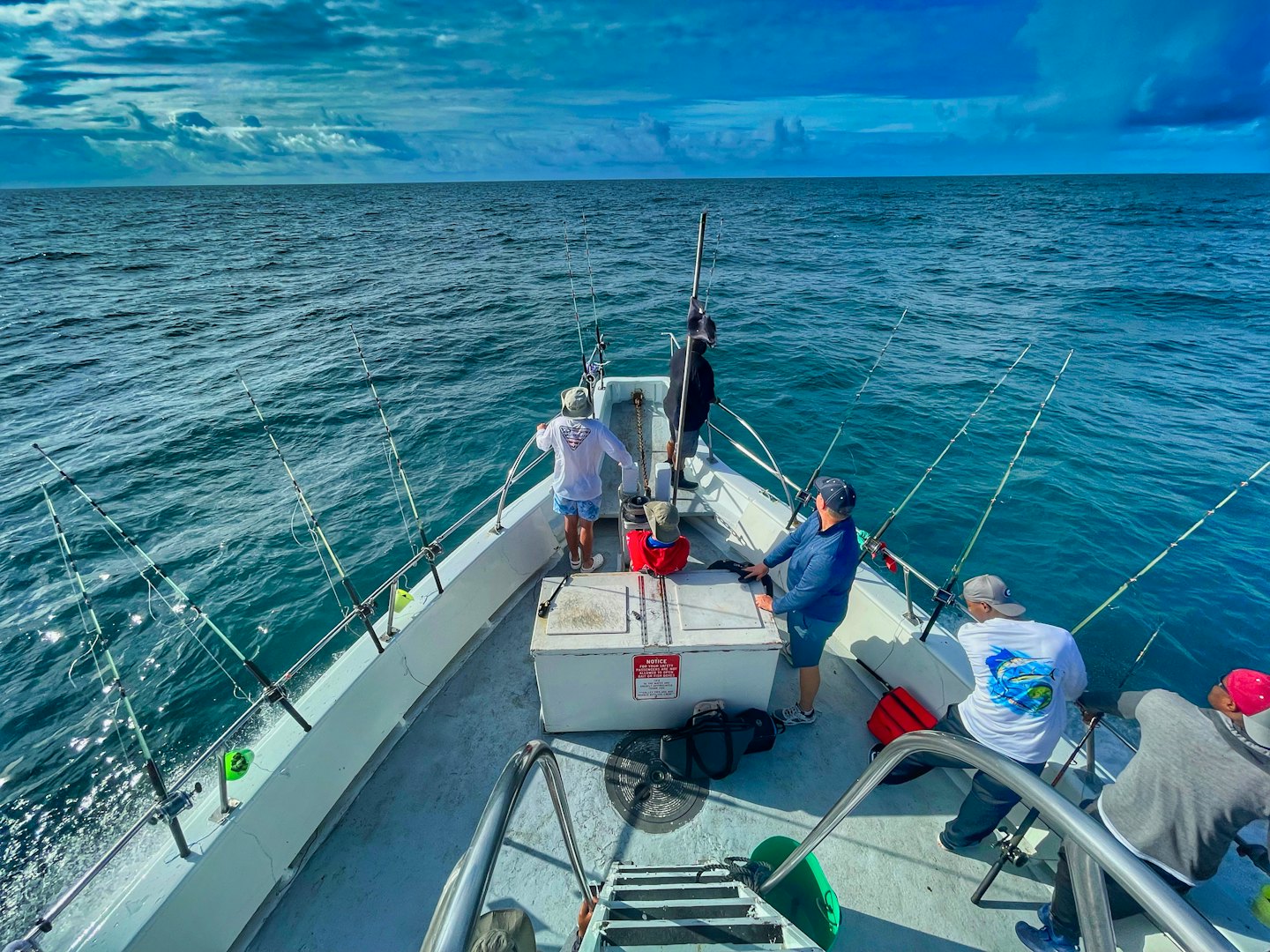 Diverse group fishing from a boat on the ocean.